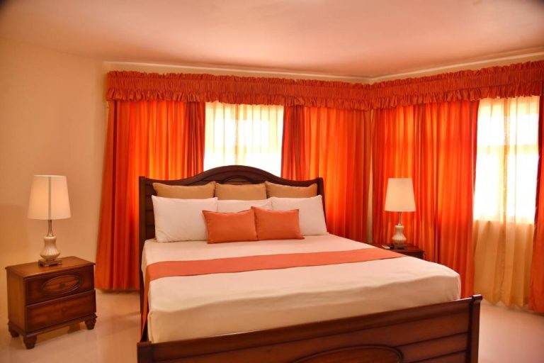 Habitación doble con cama matrimonial y cortinas naranjas en Hotel Grand A View