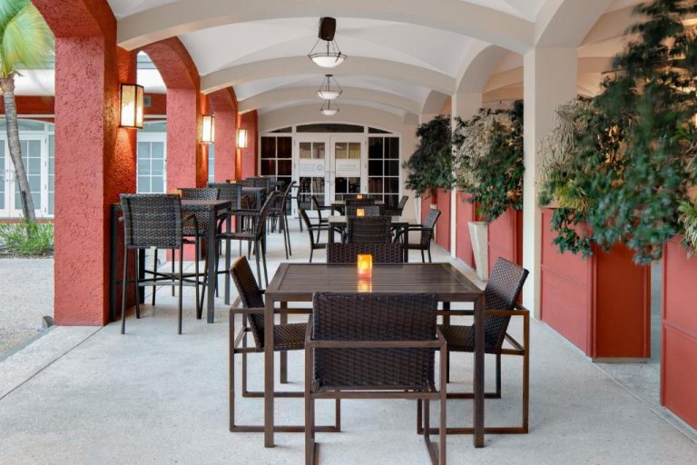 Terraza exterior con mesas y sillas de ratán del Courtyard by Marriott Bridgetown en Barbados