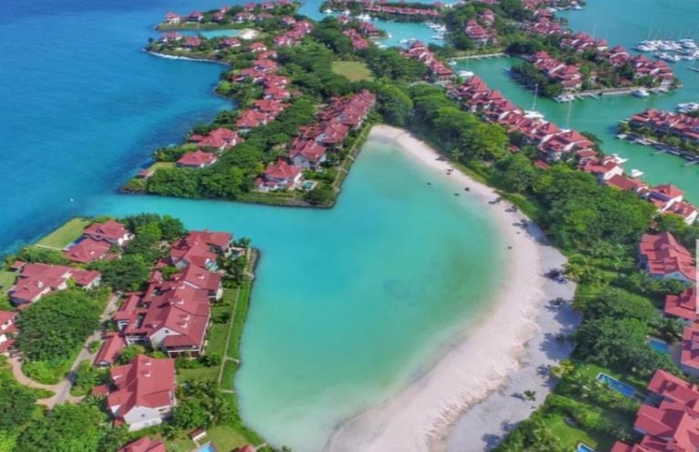 Vista aérea del complejo Eden Island con villas de tejado rojo, playa privada y aguas turquesas en Seychelles
