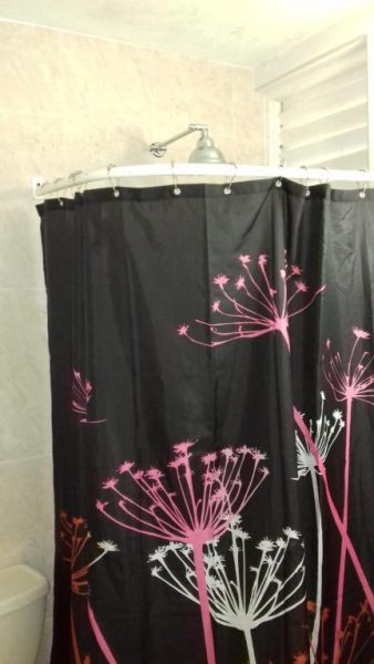 Cortina de ducha negra con diseño floral en rosa y blanco en el baño de SandCastles Holiday C9