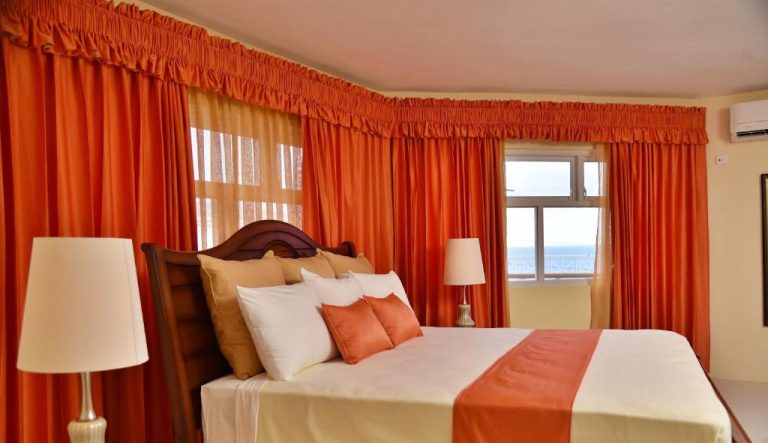 Habitación doble con cama king y cortinas naranja con vista al mar en Hotel Grand A View