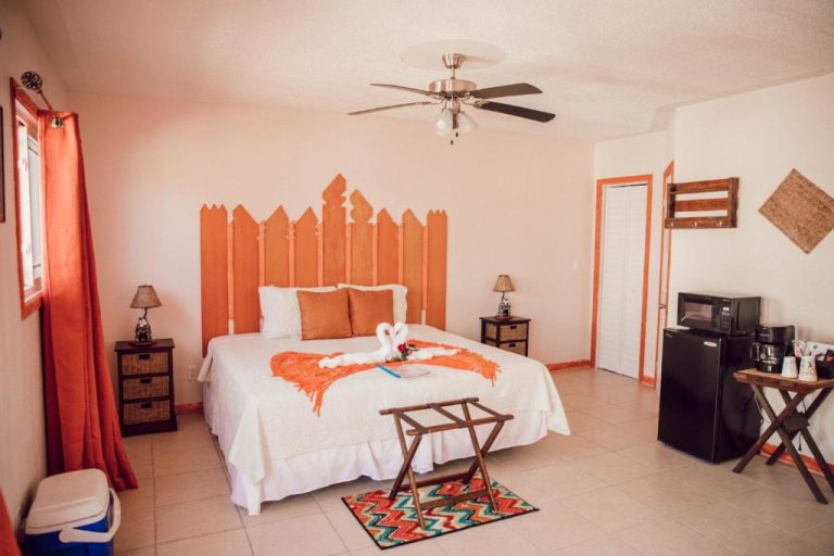 Habitación doble con cabecero de madera naranja y detalles románticos en EMBRACE Resort