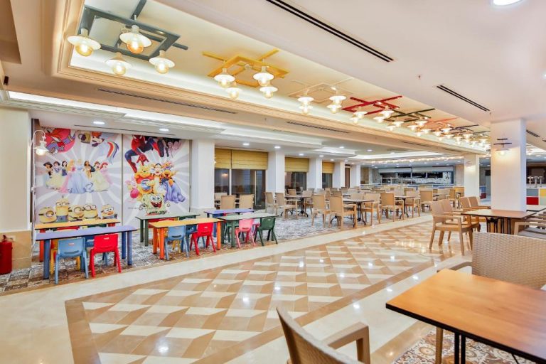 Restaurante infantil con mesas de colores y murales de personajes animados en Crystal Club World of Colours