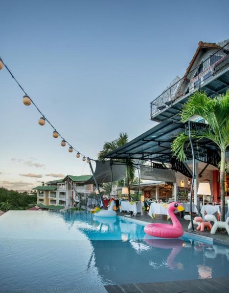 Piscina infinita con flamencos hinchables y restaurante al aire libre en La Suite Villa