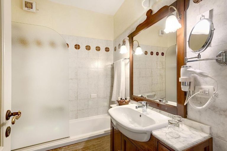 Baño clásico con bañera, lavabo de mármol y espejo de madera en Grand Hotel Smeraldo Beach