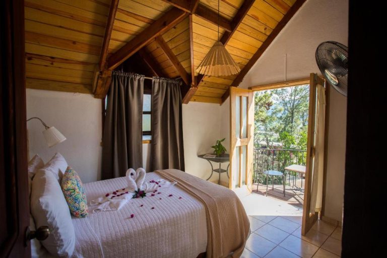 Habitación romántica con techo de madera y balcón con vista al bosque en Hotel Rancho Constanza