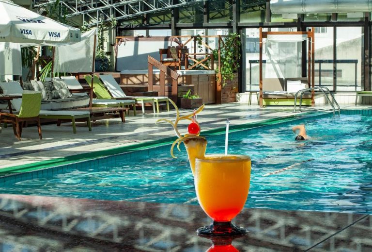 Piscina interior con cóctel tropical en primer plano del Radisson Montevideo Victoria Plaza Hotel