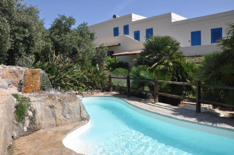 Piscina exterior con cascada de roca y jardín tropical en Marettimo Residence