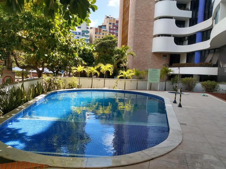 Piscina exterior azul del Studio perto do Cristo en el circuito Ondina, rodeada de palmeras y edificios