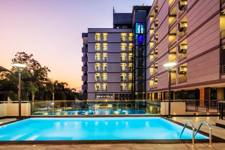Piscina exterior iluminada al atardecer del Livotel Hotel Hua Mak Bangkok con vistas al edificio