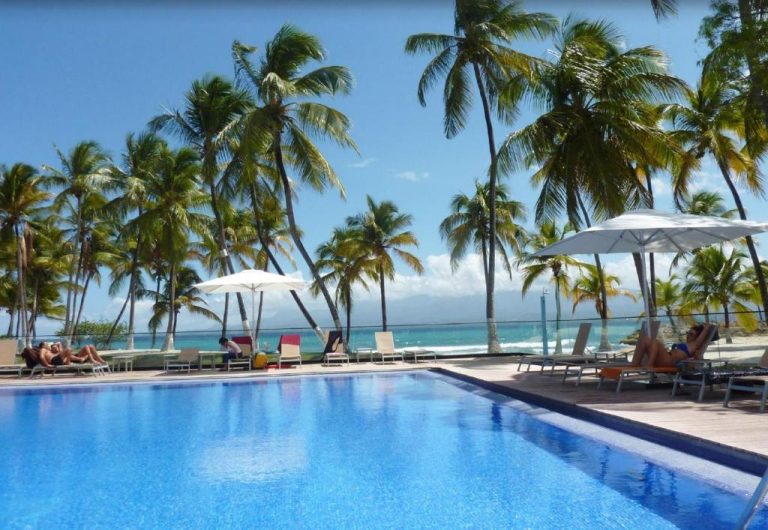 Piscina exterior con tumbonas y palmeras frente al mar caribeño en el Hotel Fleur d'Epee