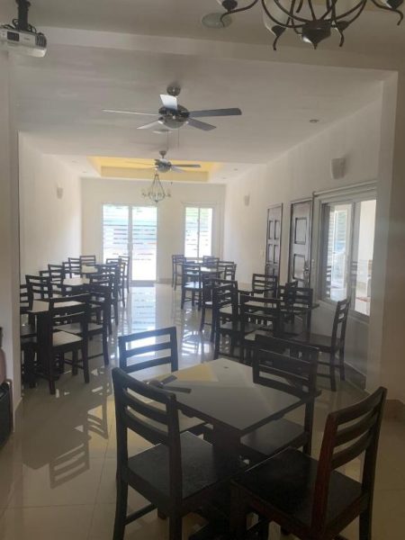 Amplio salón comedor con mesas y sillas oscuras del Hotel Tijerinos, iluminado con ventiladores de techo