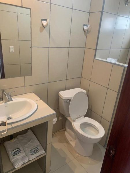 Baño completo con inodoro, lavabo y ducha en el Hotel Tijerinos, limpio y equipado con toallas