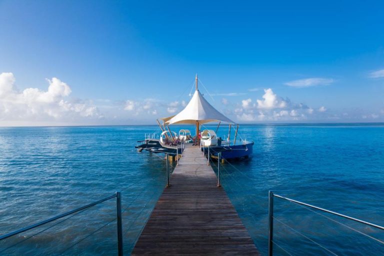 Muelle privado sobre el océano índico turquesa con carpa blanca en Coco de Mer Hotel and Black Parrot Suites