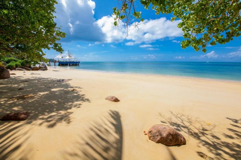 Playa de arena blanca con aguas turquesas y embarcadero del Coco de Mer Hotel en Seychelles