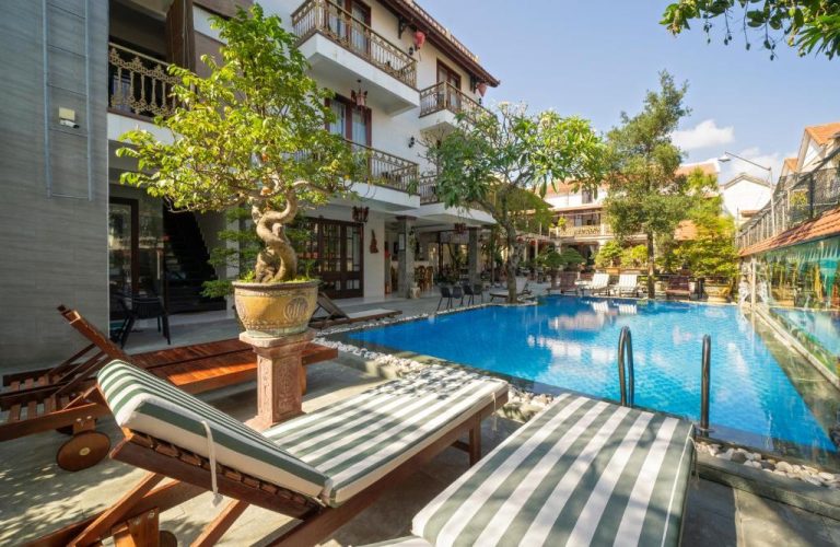Piscina exterior con tumbonas y jardín tropical del Bonsai Villa Hoi An en Vietnam