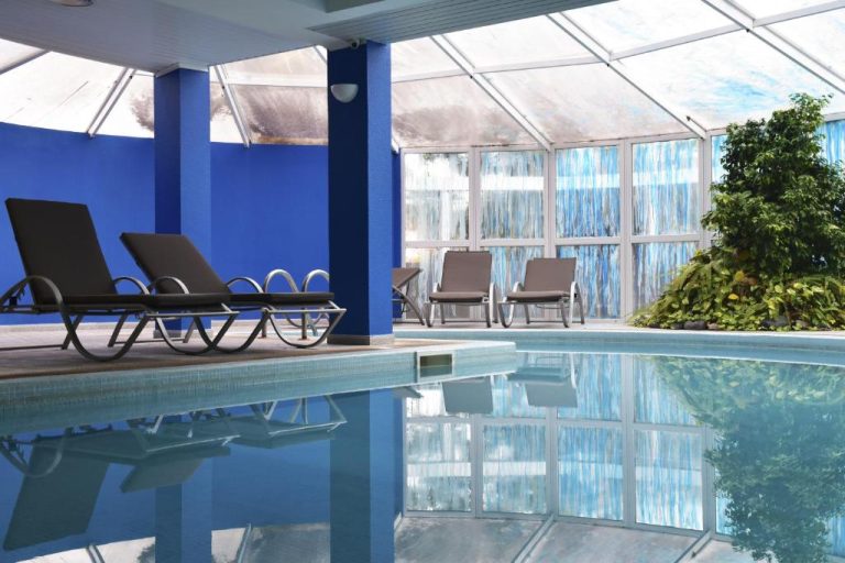 Piscina interior climatizada con tumbonas y techo acristalado del Hotel O Colmo