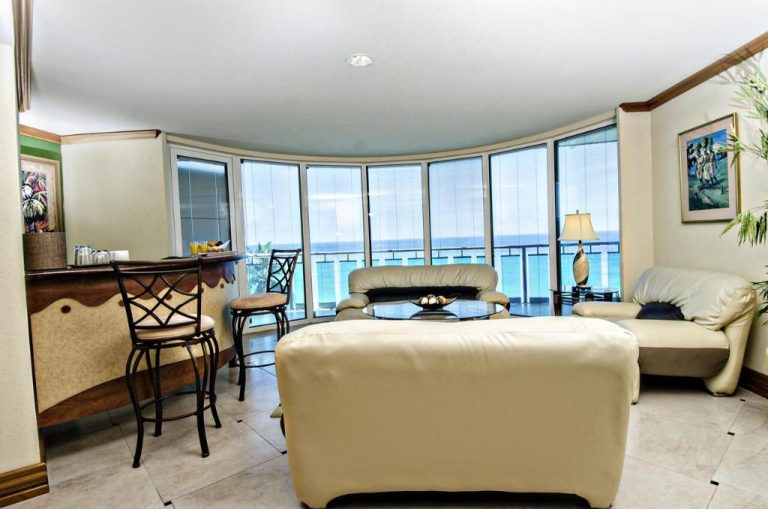 Sala de estar con sofás de cuero y vistas panorámicas al mar Caribe en Accra Beach Hotel & Spa
