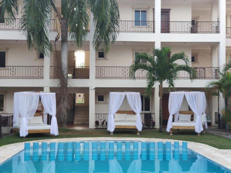 Piscina exterior con camas de dosel blancas y palmeras del hotel Bavaro Green en República Dominicana