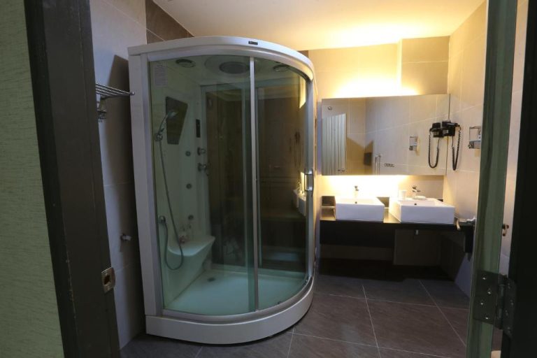 Baño moderno con cabina de ducha de cristal y doble lavabo en Kota Heritage Hotel
