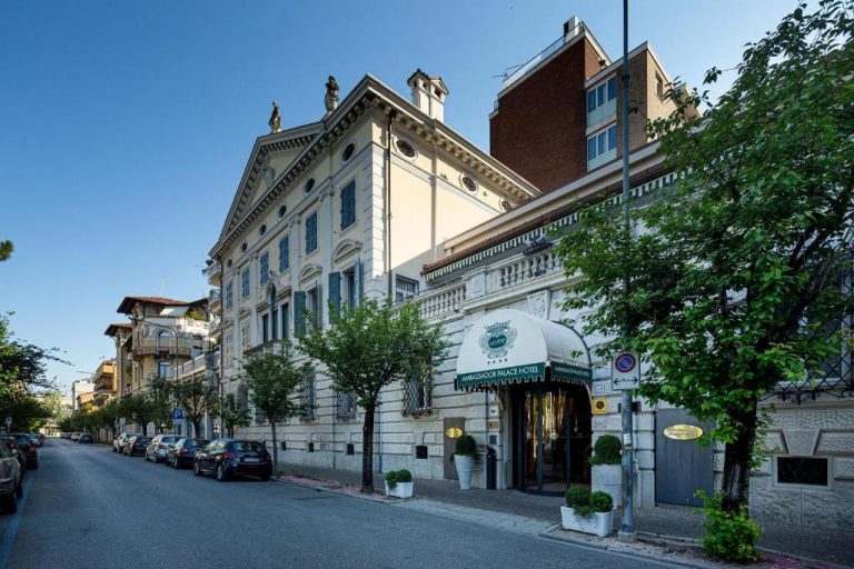 Fachada exterior clásica del Ambassador Palace Hotel con entrada principal y jardines en Italia