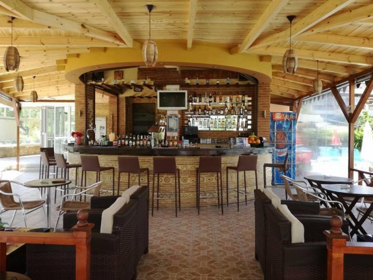 Bar exterior con barra de madera y zona de relax junto a la piscina en Daphne Studios
