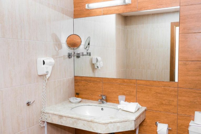 Baño moderno con lavabo de mármol, espejo y secador de pelo en Sun Palace Hotel All Inclusive