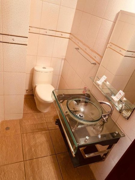 Baño moderno con lavabo de cristal y sanitario blanco en el Hotel Continental Lima