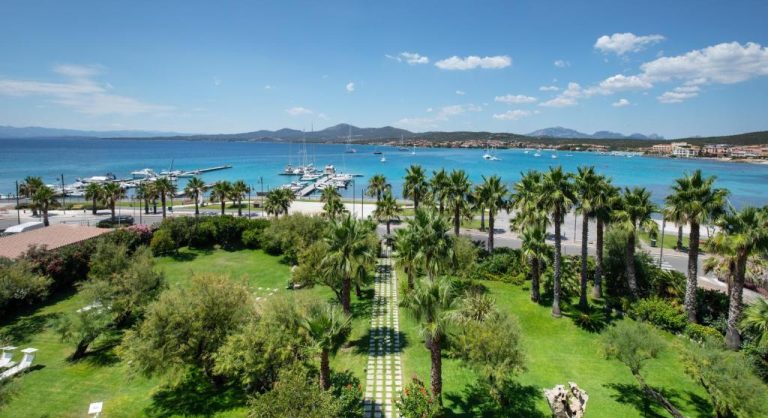 Jardín tropical con palmeras y vistas al puerto del Hotel Villa Margherita en Cerdeña