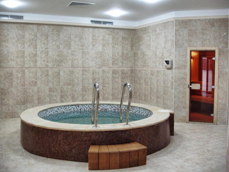 Jacuzzi circular con mosaico y acceso de acero en el spa del Kuban Resort & Aquapark All Inclusive