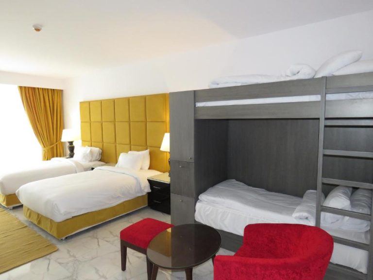 Habitación familiar con camas dobles y literas en Porto Said Hotel & Spa, decoración en amarillo y rojo