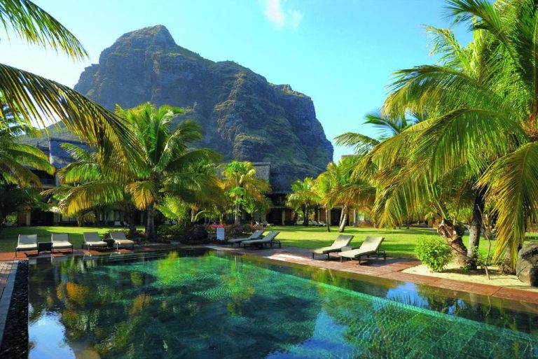 Piscina exterior con tumbonas y palmeras del Dinarobin Beachcomber Golf Resort & Spa con Le Morne al fondo