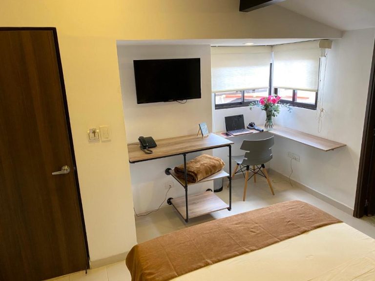 Habitación con escritorio de trabajo, TV de pared y ventana luminosa en Rivière Boutique Hotel
