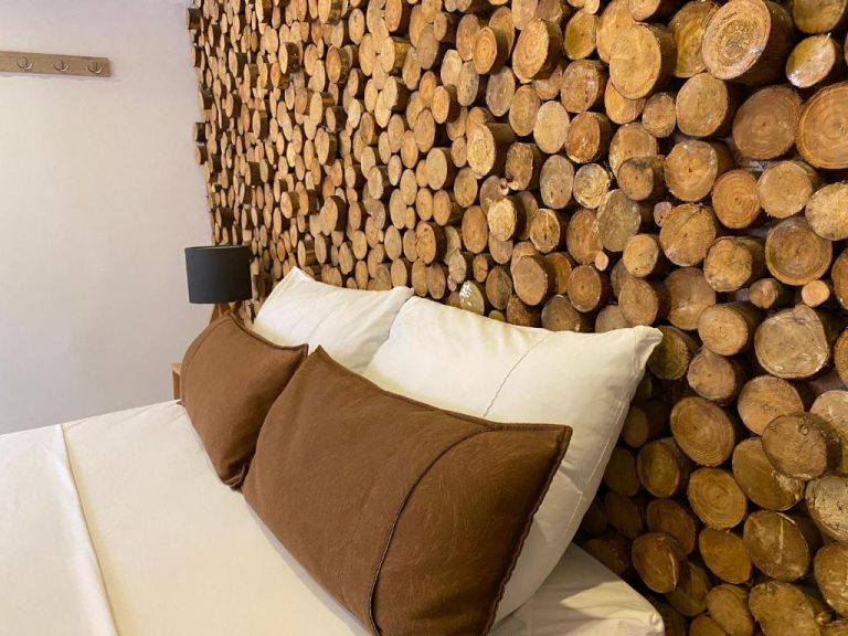 Habitación con decoración de pared de troncos de madera y cama con almohadas en Rivière Boutique Hotel