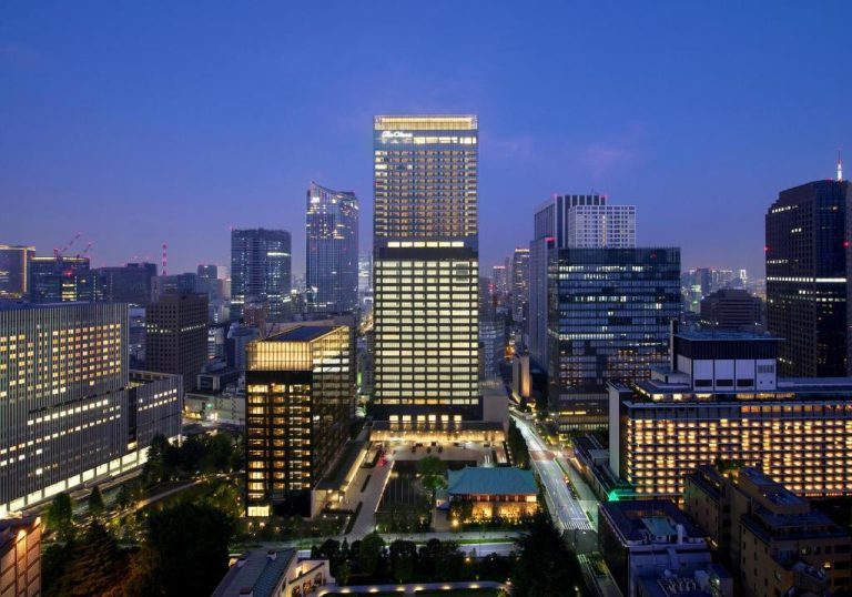 Vista aérea nocturna del The Okura Tokyo rodeado del skyline iluminado de Tokio al anochecer