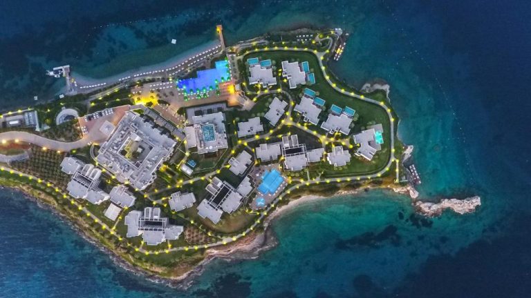 Vista aérea nocturna del complejo Xanadu Island con piscinas iluminadas y villas frente al mar