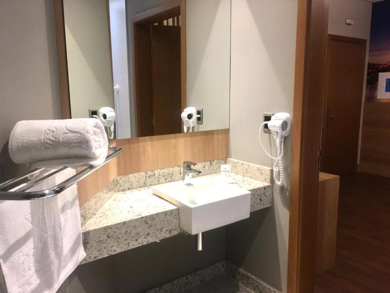 Baño moderno de Hotelog con lavabo de diseño, encimera de granito, toallas y secador de pelo