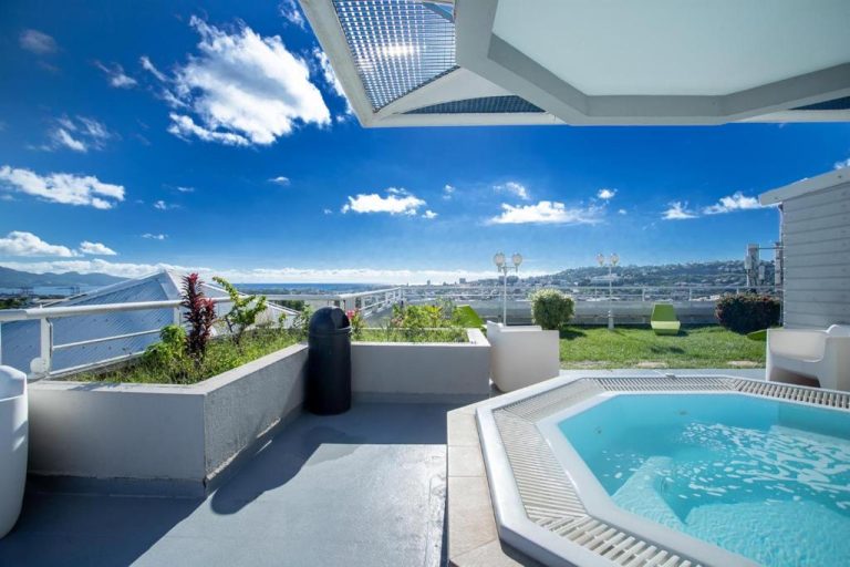 Jacuzzi privado en terraza con vistas al mar y la ciudad en Karibea La Valmenière Hôtel