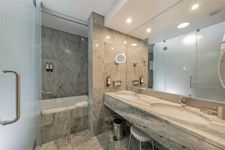 Baño de lujo con mármol gris, bañera y lavabo doble en el Hotel Marina Atlântico