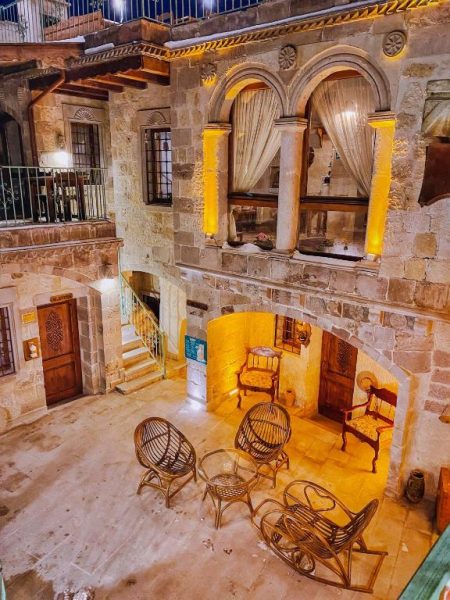 Patio interior de piedra con arcos y mobiliario de mimbre del Charming Cave Hotel en Capadocia