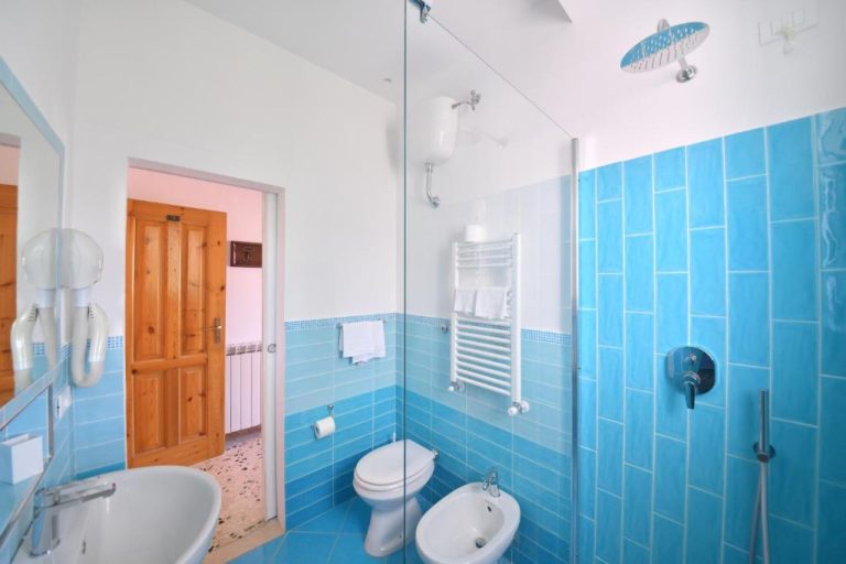 Baño moderno con azulejos azules y ducha de lluvia en el Hotel Europa