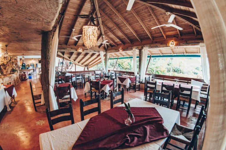 Restaurante rústico con techos de madera y mesas elegantes en Altos de Caño Hondo