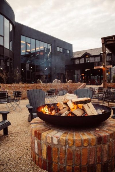 Hoguera exterior con sillas Adirondack en la terraza del Glasson Lakehouse Hotel