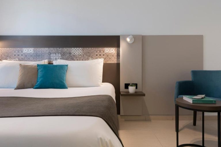 Habitación doble moderna con cama king size y detalles en azul del Bayview Hotel by ST Hotels