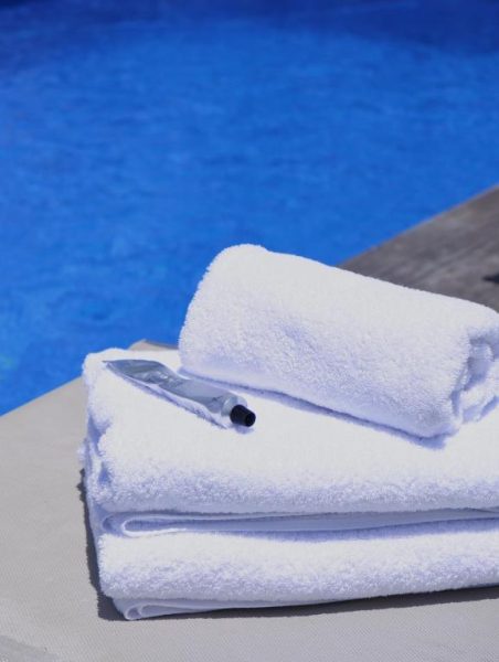 Toallas blancas y crema solar junto a la piscina del The Bahi Villa Adults Only B&B