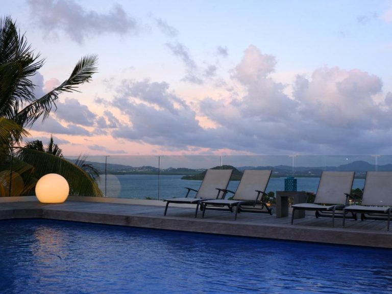 Piscina infinita con tumbonas y vista al mar al atardecer en The Bahi Villa Adults Only
