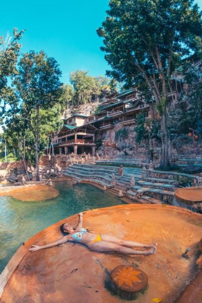 Piscina natural sobre roca con bañista relajándose en Paraíso Caño Hondo rodeado de naturaleza