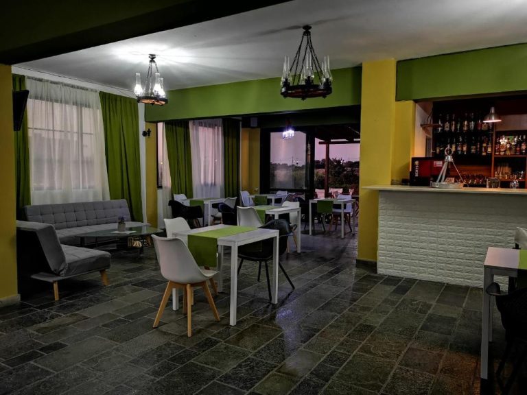 Salón restaurante y barra de bar del Hotel Ilios and Irene con decoración en verde y ambiente nocturno