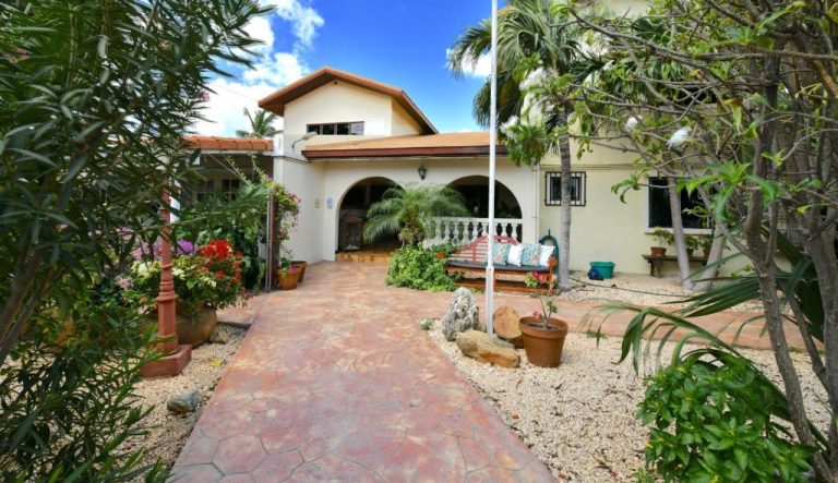 Fachada principal con jardín tropical y camino de piedra del Wonders Boutique Hotel en Aruba