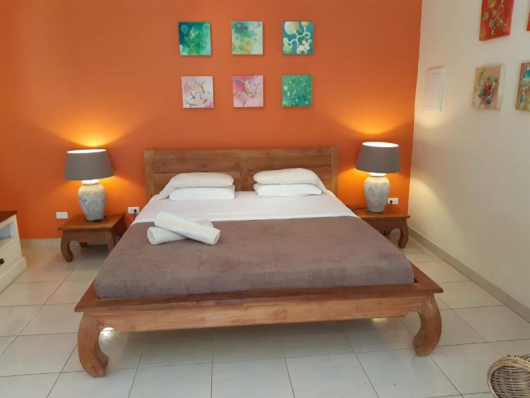 Habitación doble con pared naranja y cama de madera en Wonders Boutique Hotel
